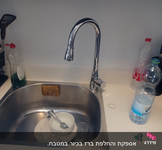 ברז כיור עם כלים ומוצרי ניקוי במטבח
